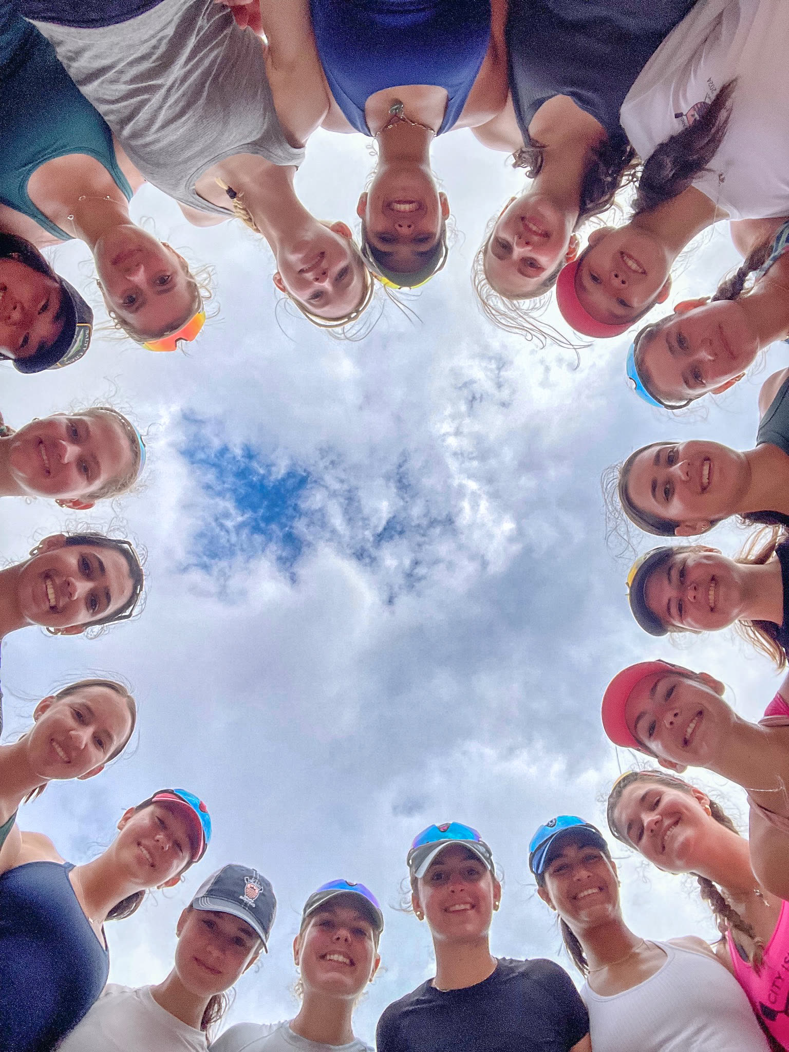 The whole team in a circle, faces in, looking down at the camera
