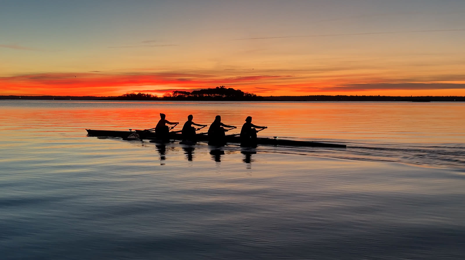 A four on glass-calm water at sunset