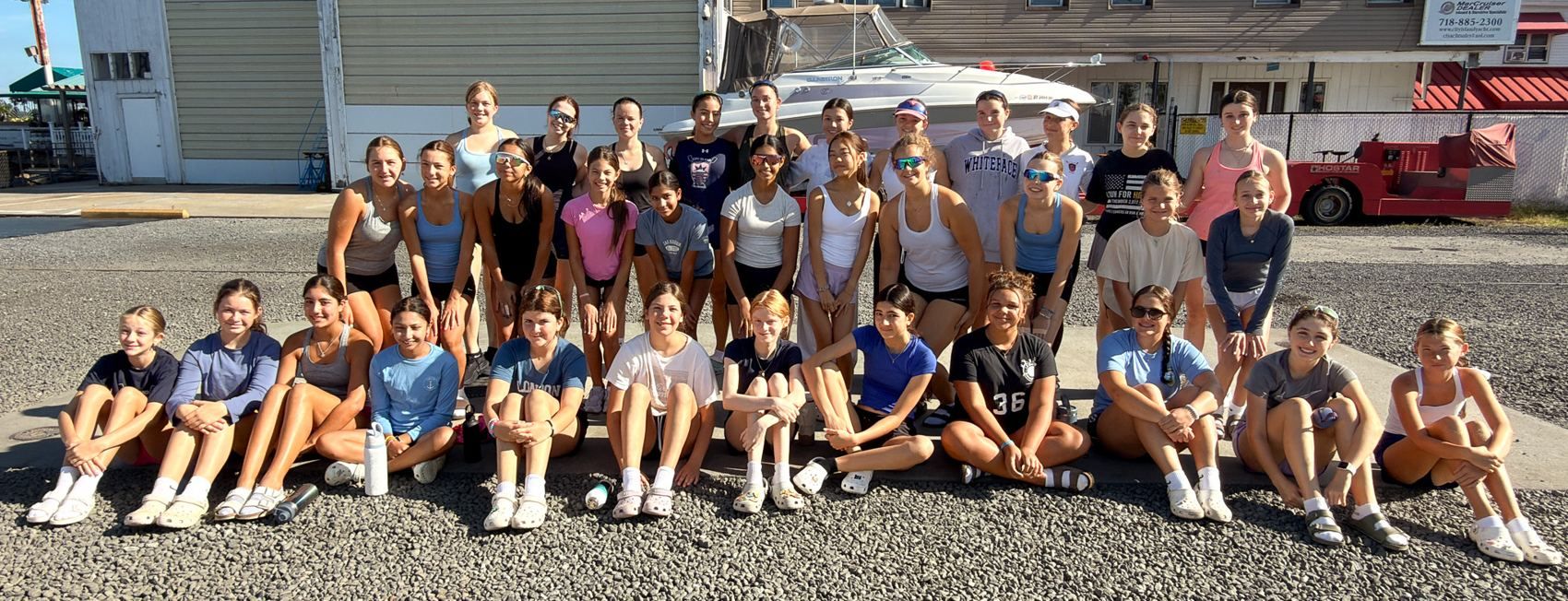 The full fall squad seated together outside the boathouse