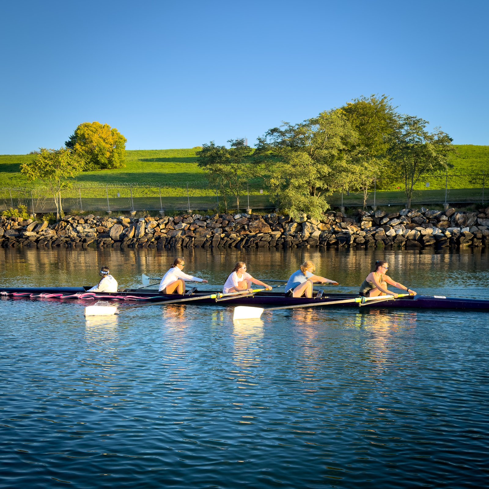 A quad on blue water in front of the green shoreline